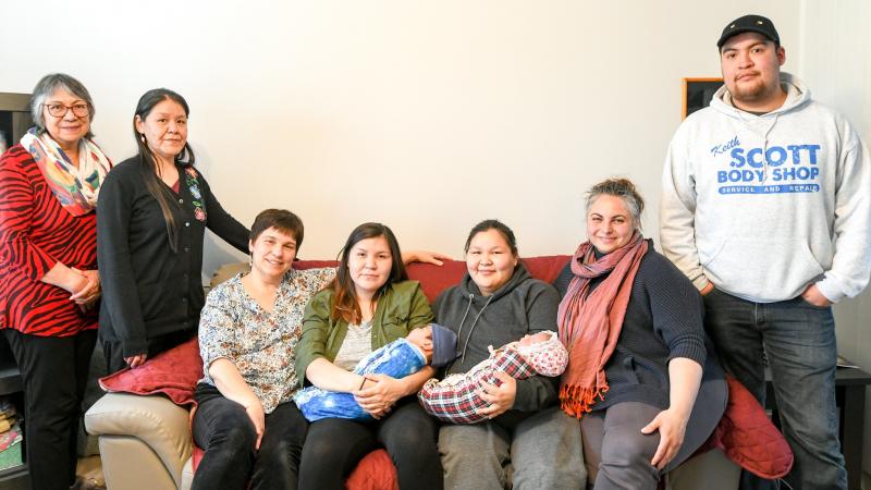 Families with babies pose with midwife