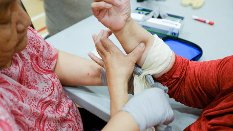 Woman applies bandage to arm