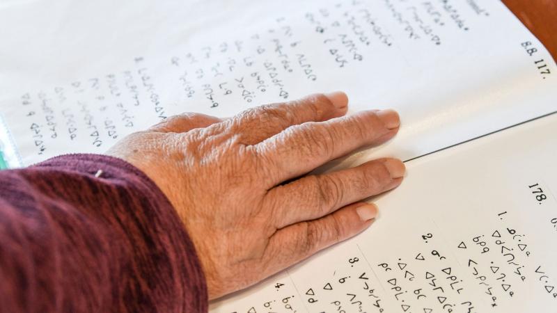 Closeup of hand on pages with text in syllabics
