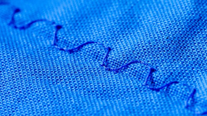 Closeup of thread on blue fabric