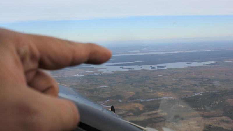 Pointing at a camp in the distance from the inside of bush plane