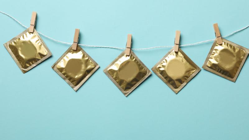 Condoms in golden packages hanging on string