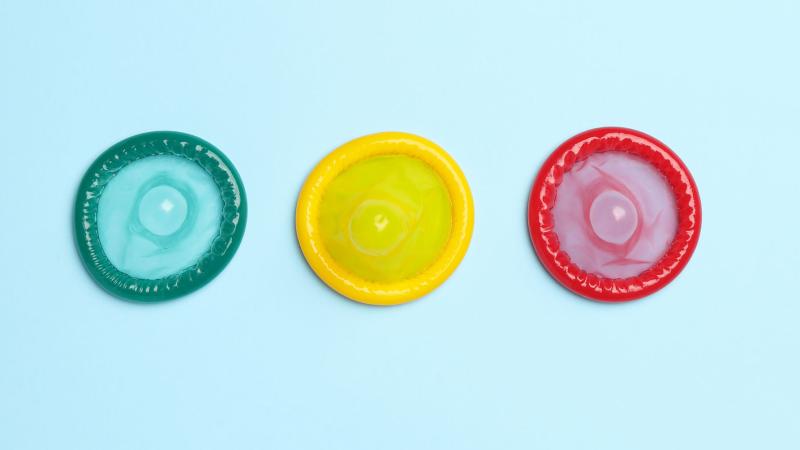 Multicoloured condoms on blue background