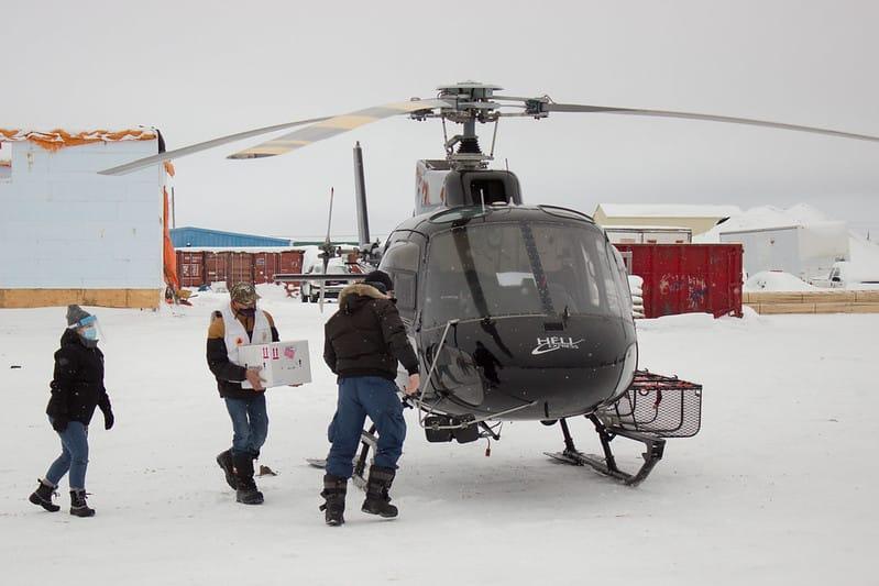Jason Coonishish carries box of vaccines to helicopter