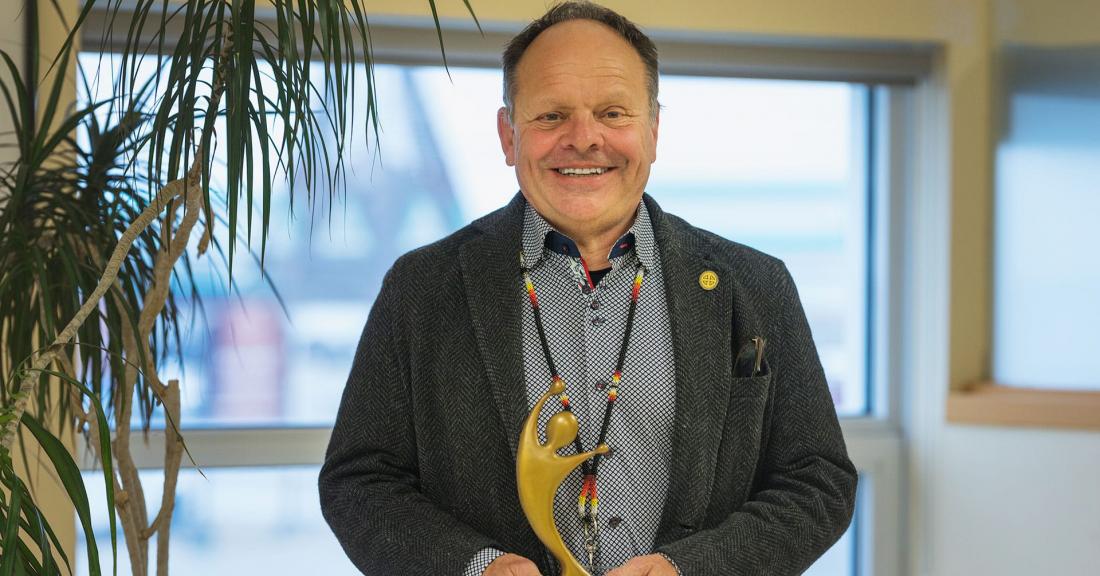 Executive Director Daniel St-Amour smiles while holding Raymond Carignan Award for Excellence