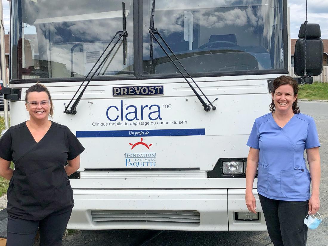 Two technicians stand in front of the Clara Bus