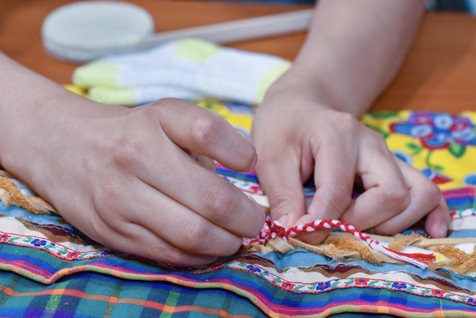 Closeup of hands sewing beads