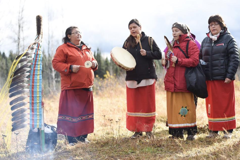 4 women in skirts singing and drumming