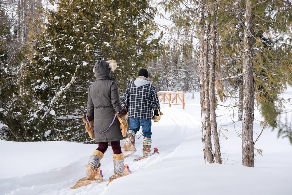 2 people walking on snowshoes along a trail