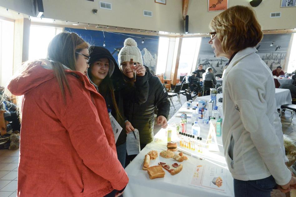 Woman explaining fat content of different foods to 3 youth