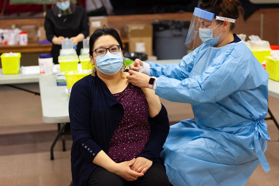 Nurse giving COVID-19 vaccine shot to woman