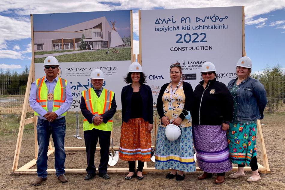 Men and women standing in front of sign announcing construction of Elders' Home