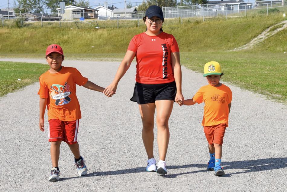 Mother and children holding hands and walking on sports track
