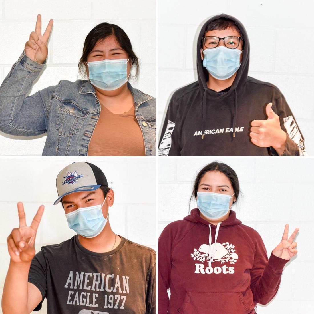 Four youth wearing medical masks hold up two fingers in a v, or give a thumbs up.