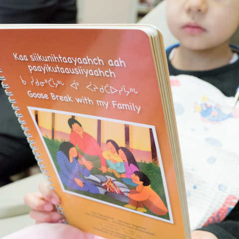Girl reading book in Cree syllabics