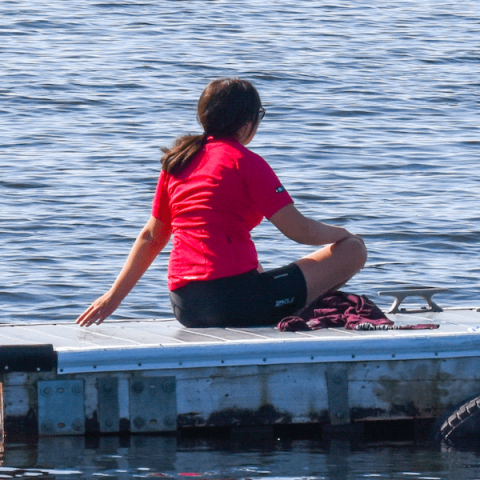 Girl sitting on jetty on lake