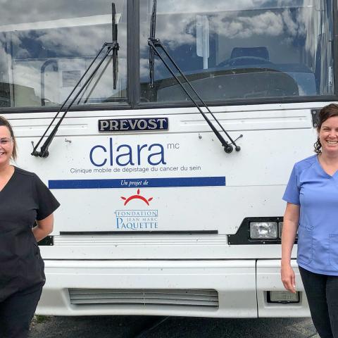 Two technicians stand in front of the Clara Bus