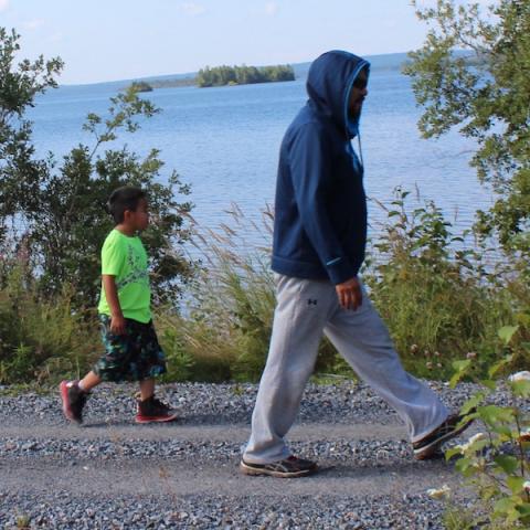Man and child walking on trail with lake in background